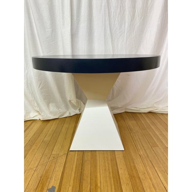 Custom lacquered linen dining table featuring a bold oval top in a deep navy blue finish paired with a sculptural white...