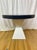Custom lacquered linen dining table featuring a bold oval top in a deep navy blue finish paired with a sculptural white...