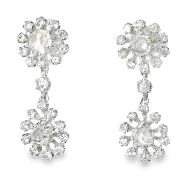 Stunning antique earrings crafted in 18K white gold, featuring an intricate floral design set with six rose-cut diamonds...