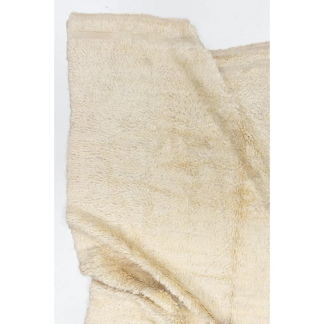 A 20th century Turkish long pile rug having an open creamy yellow field. Pics seen are with and without a flash. Measures:...