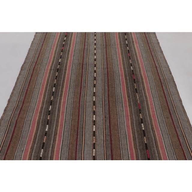 Made with handwoven wool circa 1950-1960, this 5x9 vintage Kilim enjoys fine vertical striped patterns in muted gray-...