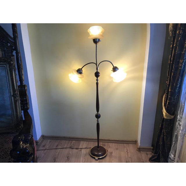 Beautiful three-arm floor lamp with glass shades, 1960s. Movable arms, wooden stand interwoven with brass sleeves, round...