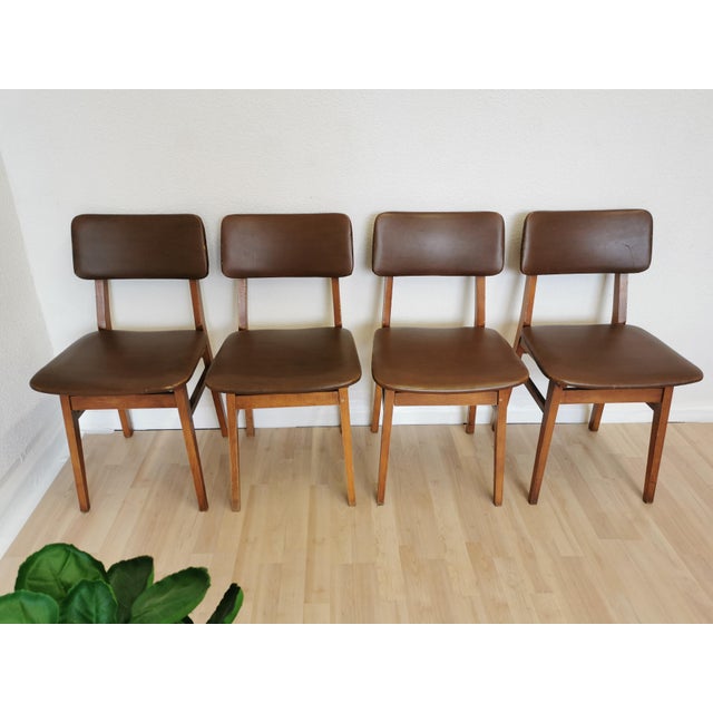 Cute vintage dining chairs are made in mid-century style from wooden base and brown leather seat and backrest. Chairs were...