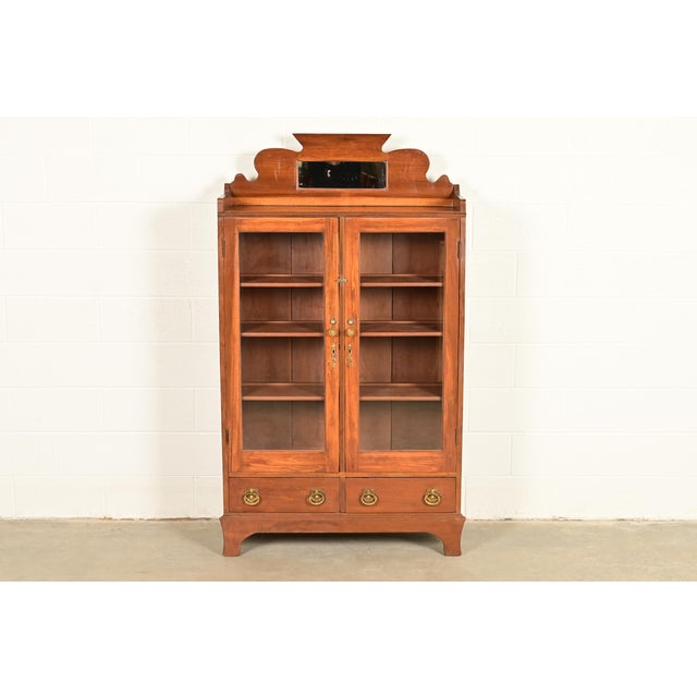 A gorgeous antique Victorian bookcase cabinet In the manner of Herter Brothers USA, Circa 1890s Carved walnut, with glass...