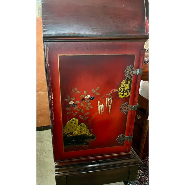 Jacobean Chinoiserie style cabinet featuring vibrant red lacquered panels adorned with hand-painted Asian-inspired scene,...