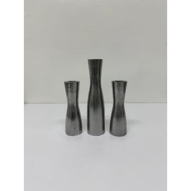 Set of three patinated polished steel candle holders by Erika Pekkari for Ikea circa 1990s. Measurements: Large - W2” D2”...