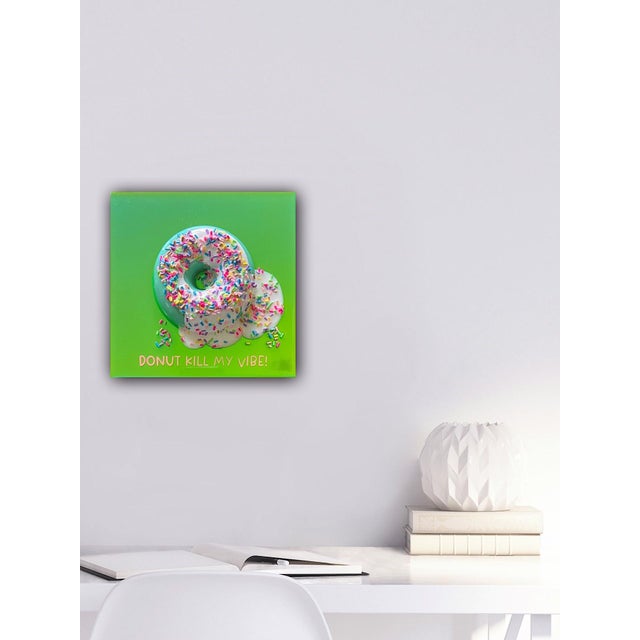 This mixed media artwork features a vibrant, oversized donut adorned with colorful sprinkles, set against a bright green...