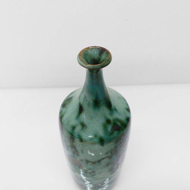 Bottle-shaped vase, made of thrown stoneware, covered with a cloudy glaze in celadon tones, deep greens punctuated by dark...