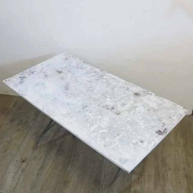 This industrial table was produced in the period 1940-1950. It is made from curved metal legs with a wooden table top.