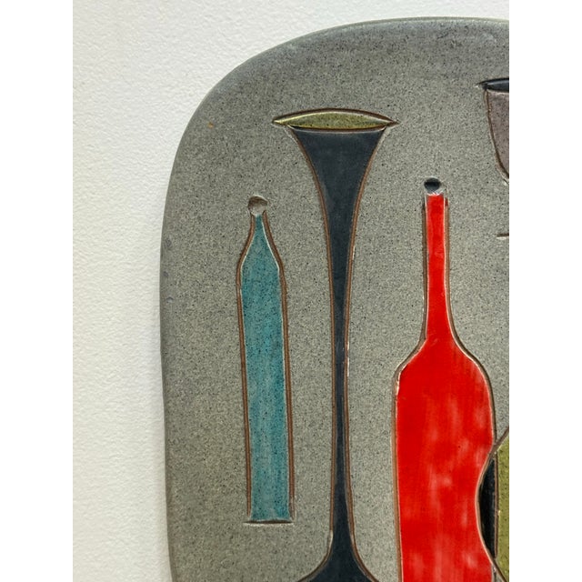 This rare plaque by Bitossi for Raymor has excellent mid century modern style circa 1955. Bottles and vases are depicted...