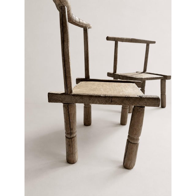An exceptional pair of antique primitive low chairs featuring extensive hand-carving. Originating from the early 20th...