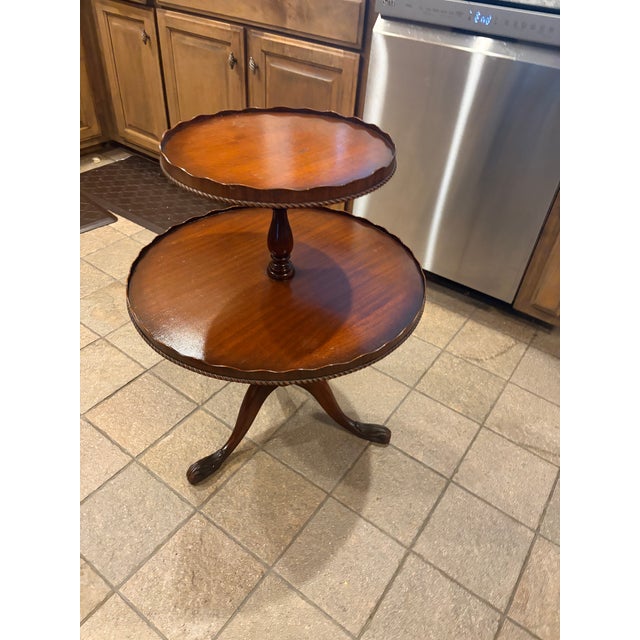 Elegant vintage two-tier dumbwaiter table in the Chippendale tradition, featuring a graduated round serving tiers with...