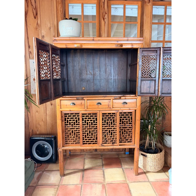 Beautiful vintage Chinese chicken coop cabinet with intricate hand-worked lattice doors, warm natural wood tones, and aged...