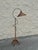 An elegant vintage floor lamp combining a sculptural black metal frame with natural woven wicker elements.
