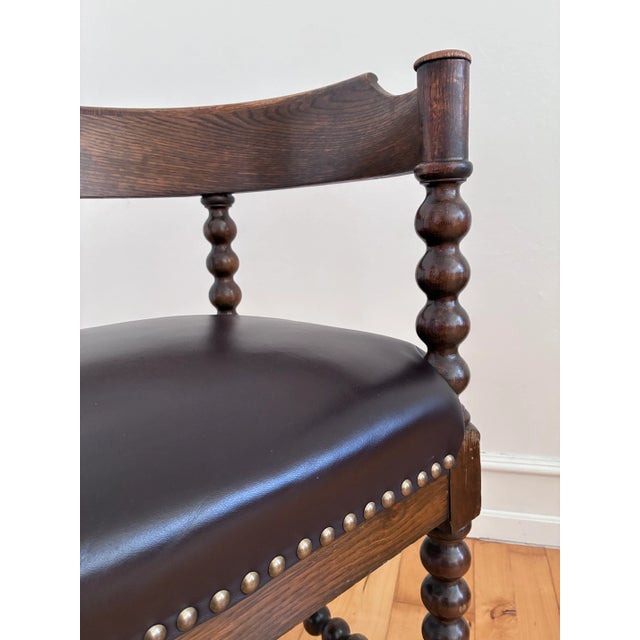 An antique corner chair in solid wood, likely beech, with a dark stained finish. The English chair features turned bobbin...