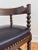 An antique corner chair in solid wood, likely beech, with a dark stained finish. The English chair features turned bobbin...
