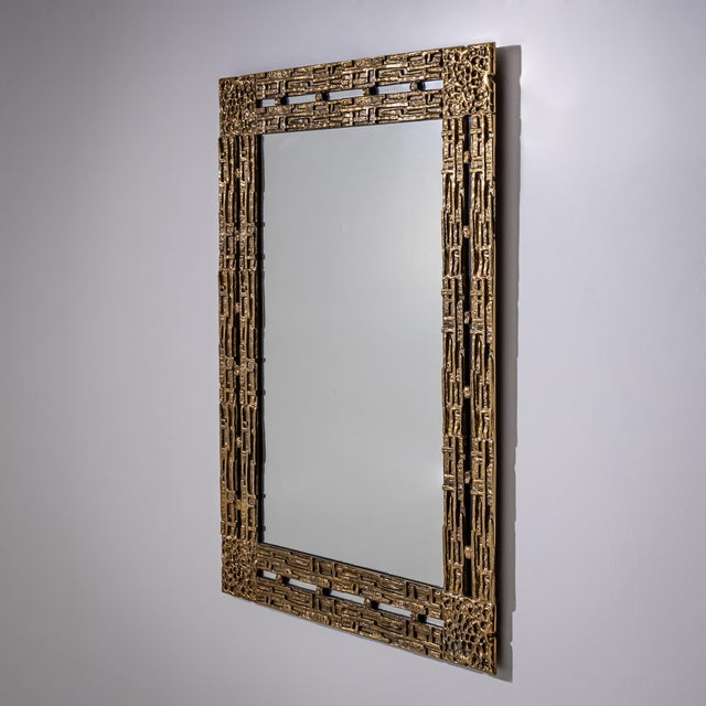 Rectangular wall mirror in a brass frame, designed by Luciano Frigerio in the 1970s. The decorative cast brass surround is...