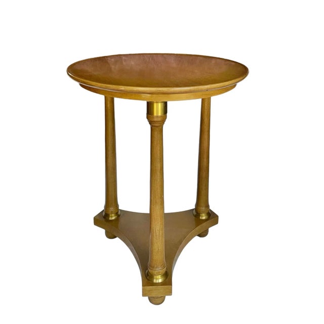 A Biedermeier occasional table of elegantly simple form featuring three column-form legs with brass capitals resting upon...