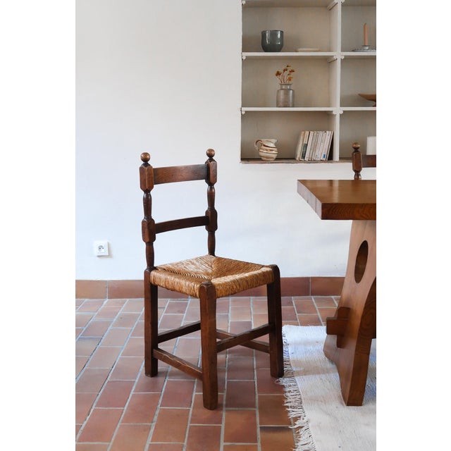 A set of six rustic dining chairs in solid oak, made in France in the 1940s in the manner of Charles Dudouyt. The back is...