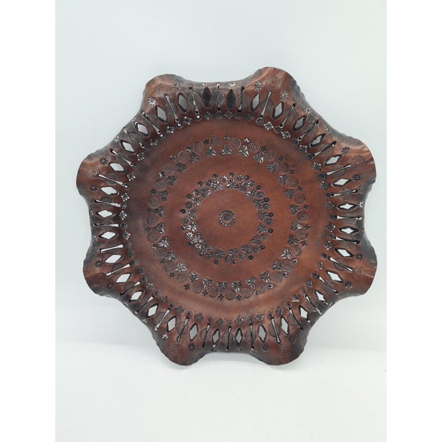 A decorative plate handmade from natural leather, richly embossed with geometric ornaments and folk motifs characteristic...