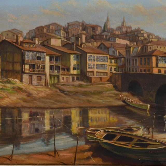 Vidal Couce's Riverside Village Scene captures the warmth and character of an old-world European town, where clusters of...