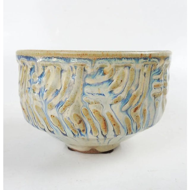 Contemporary hand thrown studio stoneware pottery bowl. Light blue and taupe glaze with raised abstract design. Unsigned.