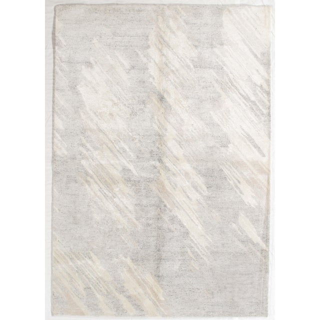 Hand-knotted modern rug featuring a soft, minimalist abstract design with subtle diagonal movement across a neutral field....