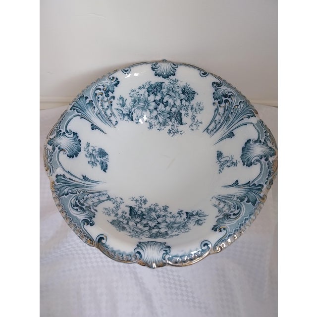 This is an antique English Flow Blue jug and basin set. It is decorated with the Flow Blue pattern, which is a bluish...