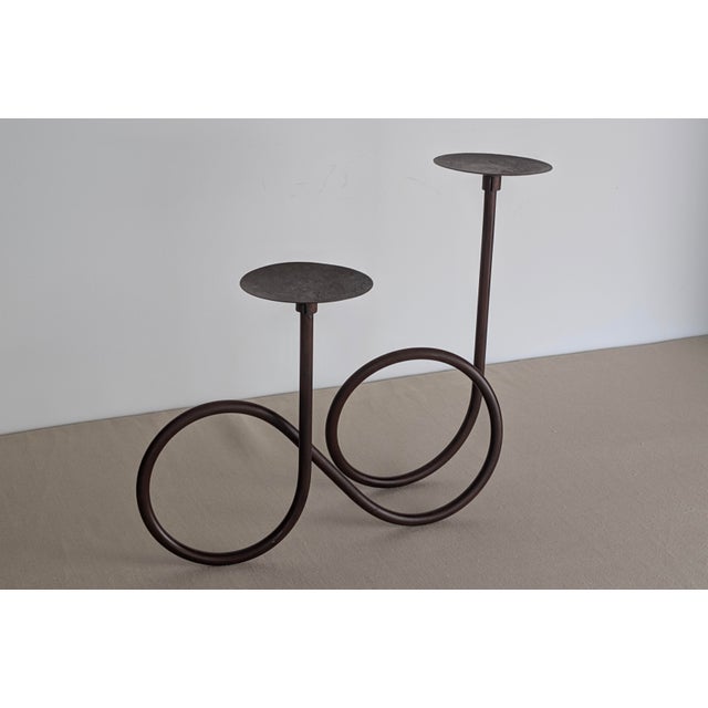 A sculptural vintage wrought iron candleholder, made in Mexico, featuring a fluid looping form with two elevated candle...
