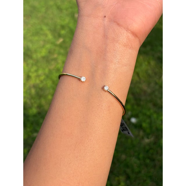 This open cuff bracelet features a 0.32 carat natural round diamond set in 14k yellow gold. Each diamond measures...