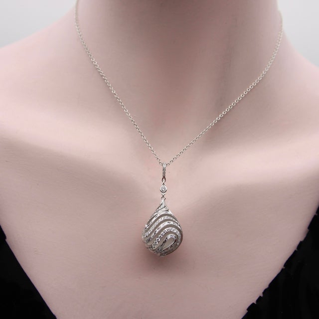 This drop-shaped rock crystal pendant is wrapped in a masterfully hand engraved and diamond encrusted cage setting. The...