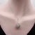 This drop-shaped rock crystal pendant is wrapped in a masterfully hand engraved and diamond encrusted cage setting. The...