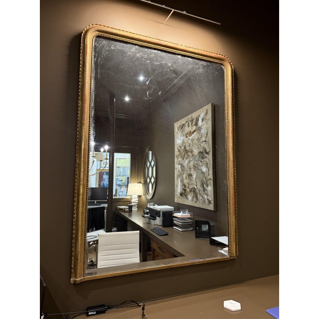 French giltwood mirror featuring a classic rectangular form with softly rounded corners, beaded inner molding, and a...