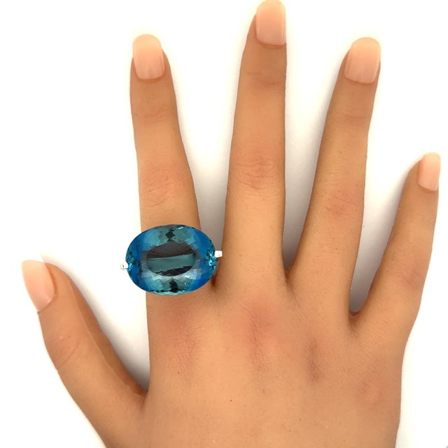 An exquisite 27.20 carat oval-cut aquamarine takes center stage in this elegant solitaire ring. The stone's captivating...