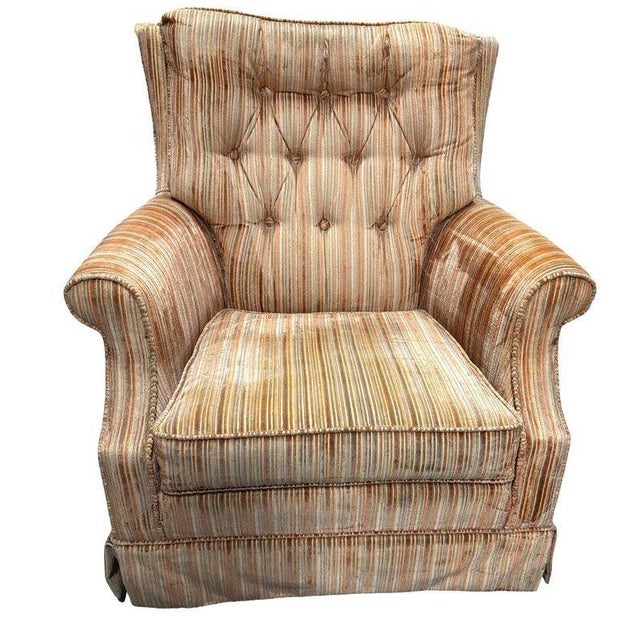 This 1970 armchair features a classic 20th century silhouette with a high, tufted back and rolled armrests all resting on...