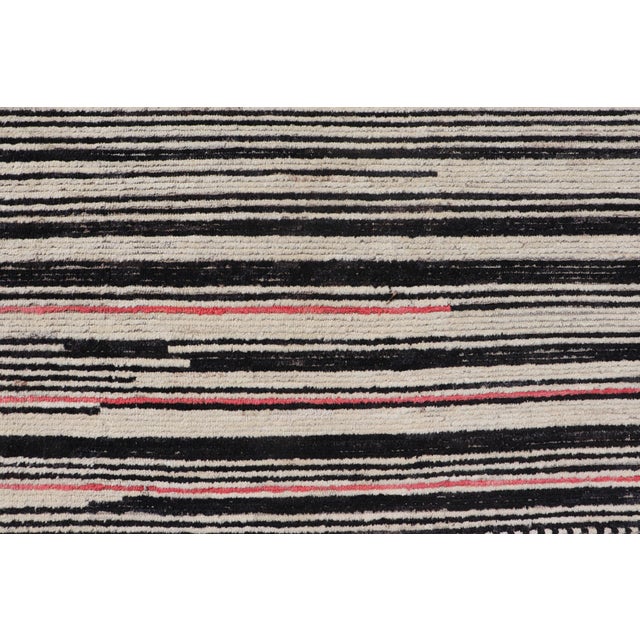 Measures: 9'9 x 12'8. This modern casual tribal rug has been hand-knotted. The rug features a modern sub-geometric...