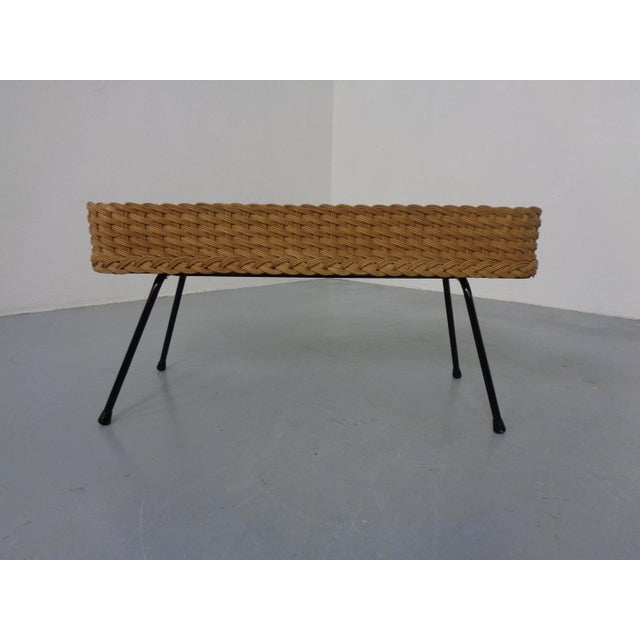 Rattan flower box with black painted metal legs.