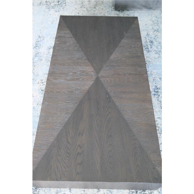 A statement-making plinth coffee table crafted in cerused dark oak, featuring a dramatic four-way book-matched starburst...