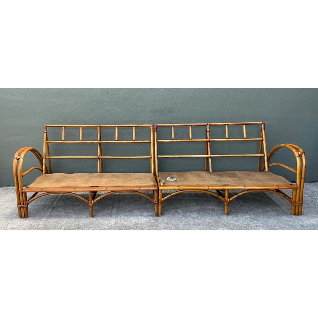 This vintage sofa frame is a long, low study in bent rattan, built as a two-section sectional with a lattice-style back...