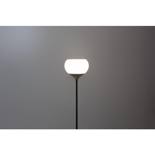 An Italian floor lamp from the 1970s with a chromed metal base and stem, featuring a flared foot and a slim column. The...