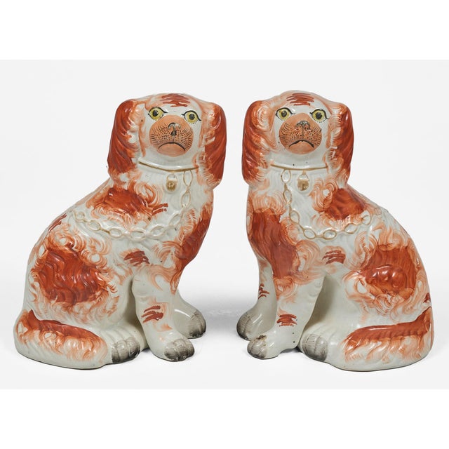 Antique pair of orange and white Staffordshire King Charles spaniels with separated legs, gold collar, gold chain and...