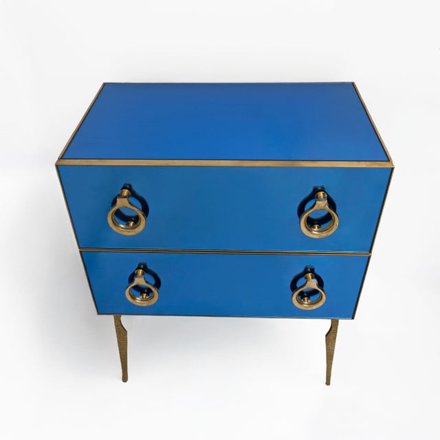 Elegant chest of drawers featuring surfaces entirely clad in blue mirror, creating sophisticated reflections of light and...