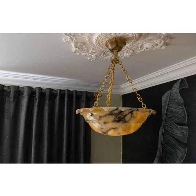 French art deco pendant light featuring richly veined yellow alabaster and brass details. a refined french art deco...