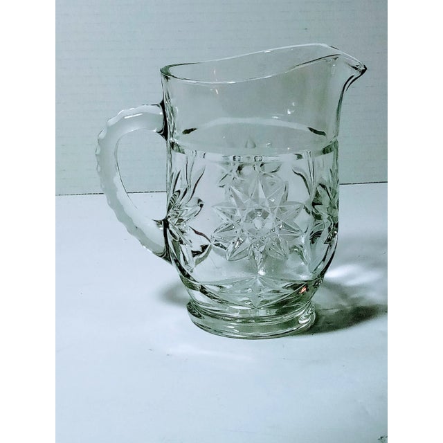 This is a small pressed glass Anchor Hocking pitcher. It was made in the 1960s and has star patterns on it. It stands 5...
