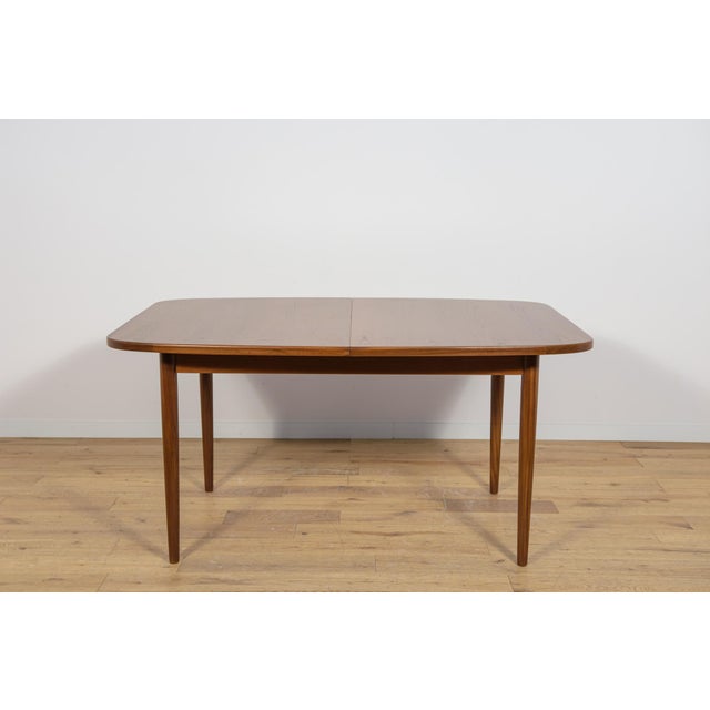 This is an rectangular shaped teak dining table manufactured by G-Plan in the 1960s. The table has reinforced edges of the...
