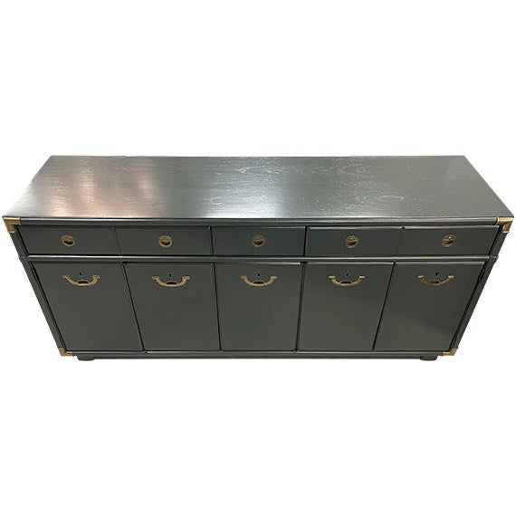 A sleek black sideboard with a long, low profile and clean paneled doors. It features brass ring pulls and small round...