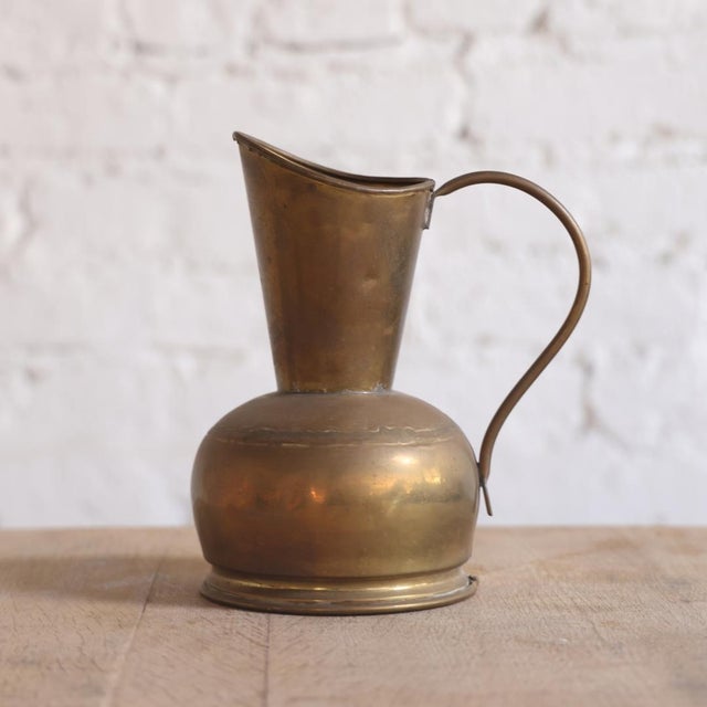 This 20th Century Belgian Brass Pitcher is a sculptural vintage vessel defined by its warm, timeworn patina and...