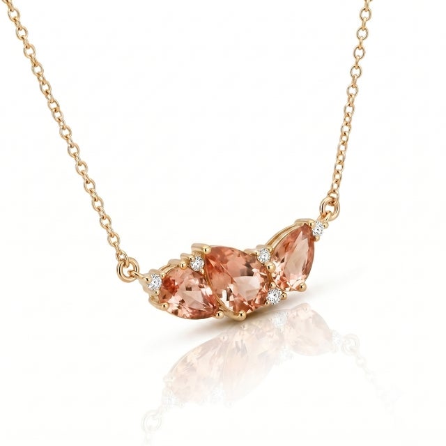 Embrace gentle warmth and understated elegance with this romantic peach-pink cluster necklace. Crafted with three teardrop...
