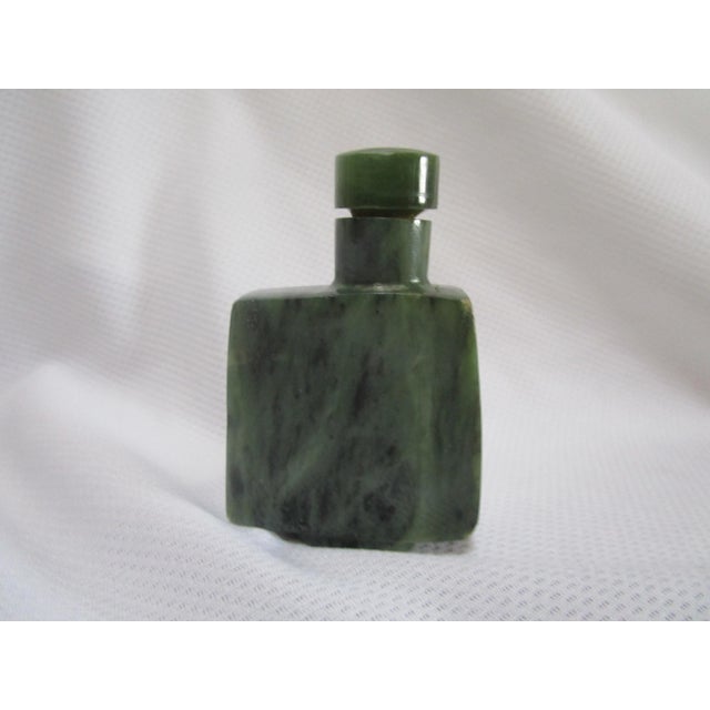 This spinach jade snuff bottle has a geometric appearance with its squared silhouette and ledge that is ergonomically...