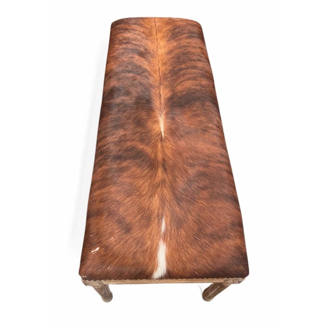 This is a bench featuring a sophisticated design with cowhide upholstery and an oak wood frame. The upholstery showcases a...